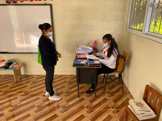 A woman standing in front of another woman sitting at a desk