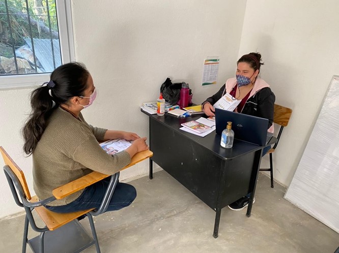 A woman sitting at a desk, with another woman seated across from her