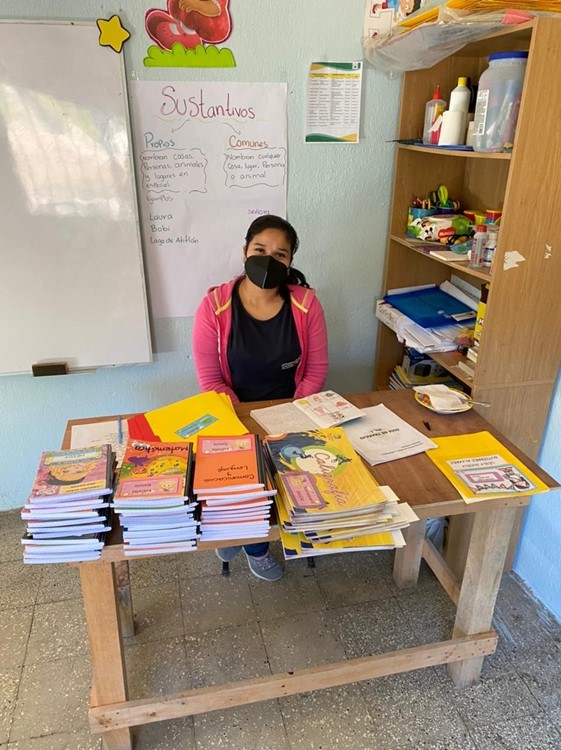 A woman sitting at a desk with stacks of books to distribute